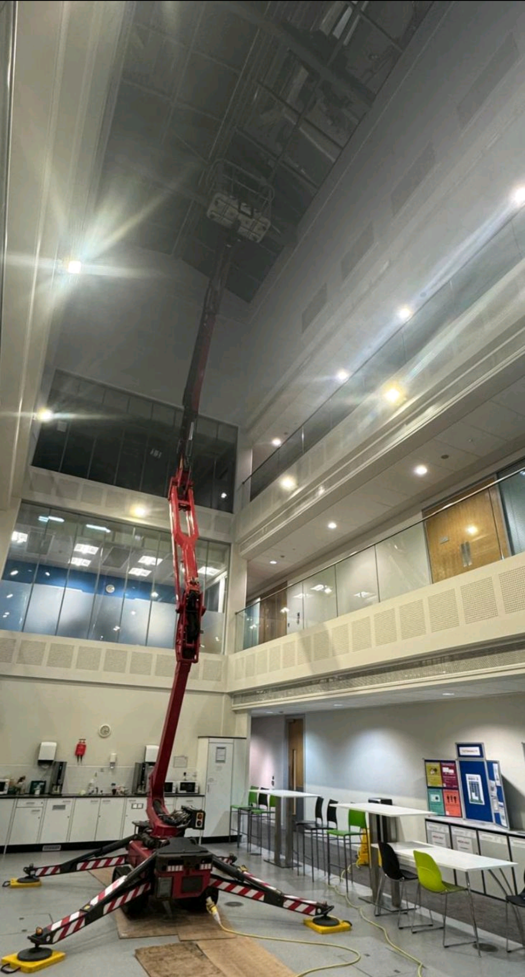 Red spider lift set inside a tall atrium with its boom extended towards the ceiling